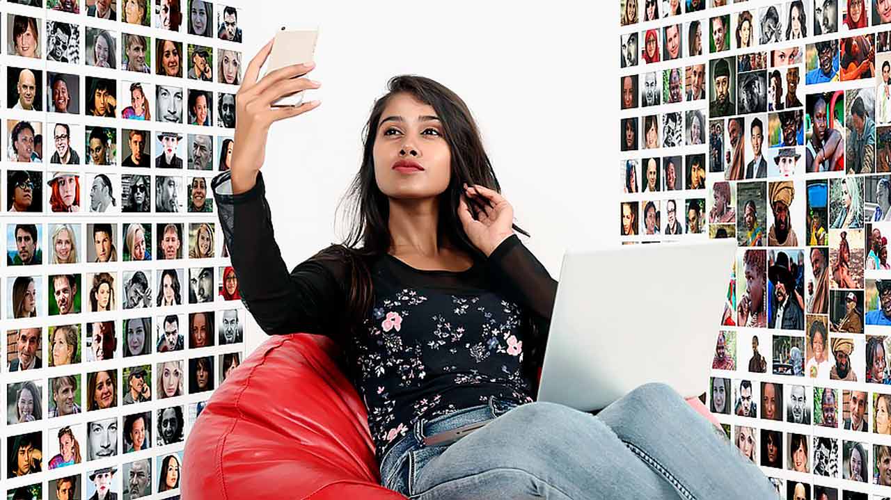 A happy Asian woman sitting in a chair, engaged in a video call on her laptop.