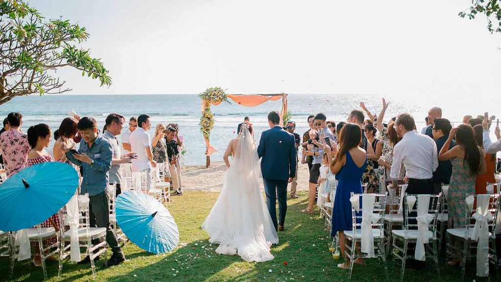 A beautiful beach wedding setup in the Philippines, with a floral arch overlooking the ocean at sunset.