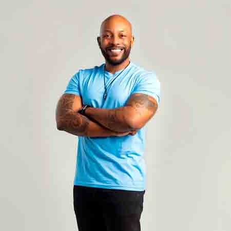 Profile photo of John, a friendly and smiling man in his late 30s, standing indoors.